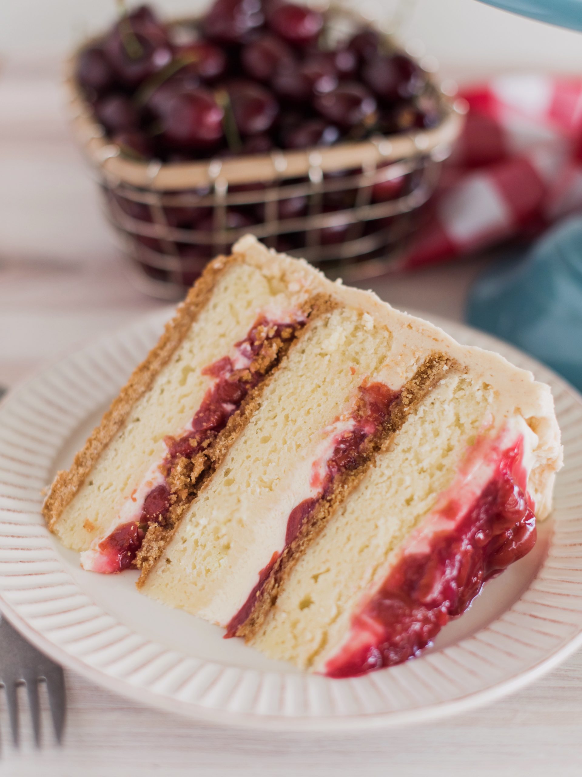 A slice of cake on a plate with cherries.